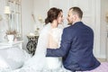 Loving couple of newlyweds with bouquit sit in bedroom