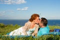 Loving couple of people are sitting on ground. The guy and the girl at sunset kissing each other in clouds with sky Royalty Free Stock Photo