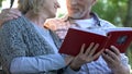 Loving couple with photobook tenderly looking at each other, pleasant moments Royalty Free Stock Photo