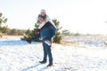 Loving couple play in the winter in the forest. Girl rides a guy in the background of the Christmas tree. Laugh and have a good Royalty Free Stock Photo