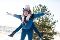 Loving couple play in the winter in the forest. Girl rides a guy in the background of the Christmas tree. Laugh and have a good Royalty Free Stock Photo