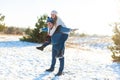 Loving couple play in the winter in the forest. Girl rides a guy in the background of the Christmas tree. Laugh and have a good Royalty Free Stock Photo