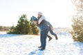 Loving couple play in the winter in the forest. Girl rides a guy in the background of the Christmas tree. Laugh and have a good Royalty Free Stock Photo