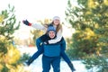 Loving couple play in the winter in the forest. Girl rides a guy in the background of the Christmas tree. Laugh and have a good Royalty Free Stock Photo