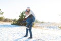 Loving couple play in the winter in the forest. Girl rides a guy in the background of the Christmas tree. Laugh and have a good Royalty Free Stock Photo