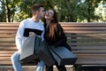 Loving couple resting on bench in park with paper bags after successful shopping. Nice date Royalty Free Stock Photo