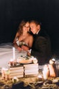 Loving couple share a romantic dinner with candles and cake at beach, coast against wonderful night Royalty Free Stock Photo