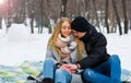 A loving couple are sitting on a blanket and holding hands in the winter. The guy holds the girl by the hand on the street in