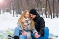 A loving couple are sitting on a blanket and holding hands in the winter. The guy holds the girl by the hand on the street in