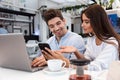 Loving couple sitting in cafe using laptop computer and mobile phone Royalty Free Stock Photo