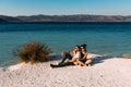 Loving couple sitting on the edge of the cliff by the sea. Wedding travel. Honeymoon trip. Boy and girl at the sea