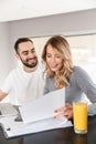 Loving couple sitting at the kitchen using laptop computer and work with documents Royalty Free Stock Photo