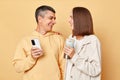 Loving couple spending free time together woman and man wearing casual style clothing standing isolated over beige background