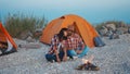 Loving couple spending time together by campfire during romantic camping holidays with tents