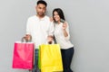 Loving couple standing over grey wall and holding shopping bags Royalty Free Stock Photo