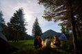 Loving couple surrounded by friends at an evening camping in the mountains. Royalty Free Stock Photo