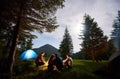 Loving couple surrounded by friends at an evening camping in the mountains.