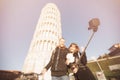 Loving couple takes selfie photo on stick and camera against background of leaning Tower Pisa, Italy. Travel concept Royalty Free Stock Photo