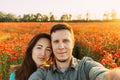 Loving couple taking photo selfie in poppy flower meadow. Royalty Free Stock Photo