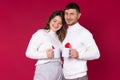 A loving couple with two white cups of tea for your add are smiling on a red background. Red hearts Royalty Free Stock Photo