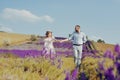 A loving couple is walking along the lavender field, a girl in a dress and a straw hat with a man holds hands and walks through Royalty Free Stock Photo