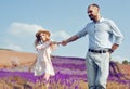 A loving couple is walking along the lavender field, a girl in a dress and a straw hat with a man holds hands and walks through Royalty Free Stock Photo