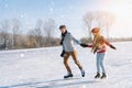 Loving couple in warm sweaters having fun on ice. Woman and man ice skating outdoors in sunny snowy day. Active date on Royalty Free Stock Photo