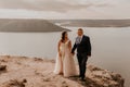 loving couple wedding newlyweds in white dress and suit walk in summer on mountain above river