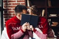 Loving couple in winter jumpers kissing hiding behind the book.