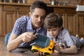 Loving dad have fun playing repairing car with small son Royalty Free Stock Photo