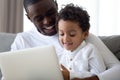 Loving dad relax using laptop with little biracial son Royalty Free Stock Photo