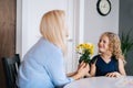 Loving daughter gives bouquet flowers to her mother. Girl gives a gift to her beloved mother.