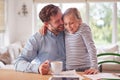 Loving Daughter At Home With Father Sitting At Table With Paperwork