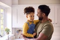 Loving Daughter Hugging Army Father In Uniform On Home Leave In Kitchen