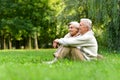 Elderly couple sitting on green grass in the summer park Royalty Free Stock Photo