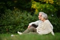 Portrait of elderly couple sitting on green grass in the summer park Royalty Free Stock Photo
