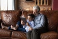 Loving elderly grandfather embrace preteen grandkid playing game on touchpad Royalty Free Stock Photo