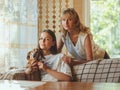 Loving elderly mother hug adult 20s daughter from behind while daughter sitting on couch and holding their dog. looking at camera Royalty Free Stock Photo