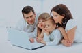 Loving family looking at a laptop lying down on bed at home. Royalty Free Stock Photo