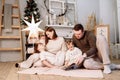 Loving family. Mom, dad with little daughters read interesting book and having fun near decorated fir tree and fireplace Royalty Free Stock Photo