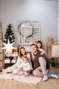 Loving family. Mom, dad with little daughters read interesting book and having fun near decorated fir tree and fireplace Royalty Free Stock Photo