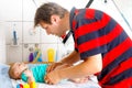 Loving father changing diaper of his healthy cute baby daughter. Little child, girl on changing table in bathroom with Royalty Free Stock Photo