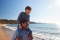 Loving Father Giving Son Ride On Shoulders As They Walk Along Beach Together