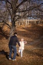 Loving father playing with little daughter both having fun and smiling having walk in forest with dry fallen leaves on Royalty Free Stock Photo