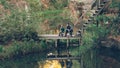 Loving father is teaching his son to catch fish on autumn day, people are sitting on wooden pier with rods and talking Royalty Free Stock Photo