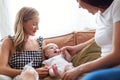Loving Female Same Sex Couple Cuddling Baby Daughter On Sofa At Home Together Royalty Free Stock Photo