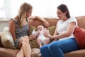 Loving Female Same Sex Couple Cuddling Baby Daughter On Sofa At Home Together Royalty Free Stock Photo