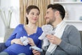 loving future parents on sofa holding booties and soft-toy Royalty Free Stock Photo