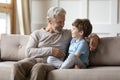 Loving granddad sit on sofa talking with small grandson