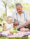 Loving Grandfather and Granddaughter Coloring Easter Eggs on Blanket At
